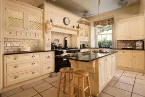 una gran cocina con armarios blancos y 2 taburetes en Fairnilee House en Galashiels