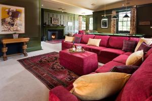 a living room with a red couch and a fireplace at Fairnilee House in Galashiels