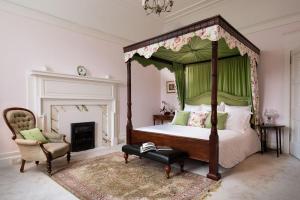 1 dormitorio con cama con dosel y silla en Fairnilee House en Galashiels