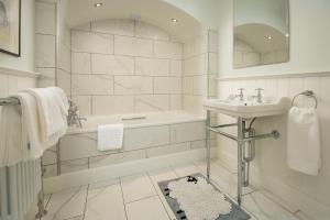 een witte badkamer met een bad en een wastafel bij Fairnilee House in Galashiels
