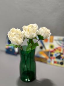 Un jarrón verde con flores blancas. en Bcube - santa Bona Bed & Breakfast, en Pisa