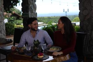 a man and a woman sitting at a table with food at Hacienda Los Molinos Boutique Hotel & Villas in Boquete