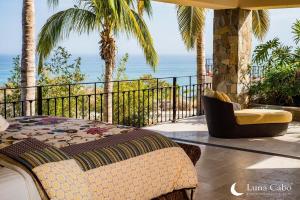 a bed and a chair on a balcony with the ocean at Firepit Sunsets, Hot Tub Soaks, BBQ, Ocean Views in San José del Cabo