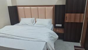 1 dormitorio con 1 cama grande con sábanas y almohadas blancas en Laxman Guest House varanasi, en Varanasi
