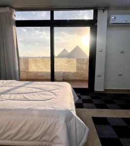 a bedroom with a view of the pyramids from a window at Tapiri pyramids inn in Cairo