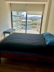 a bed in a room with a large window at Departamento en Zona Real/Acueducto in Guadalajara