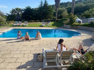 un groupe de personnes assises autour d'une piscine dans l'établissement Casa Calidris - Bed, Wine & Breakfast, à Sesimbra