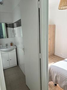 a white bathroom with a sink and a bed at Soleil urbain in Périgueux