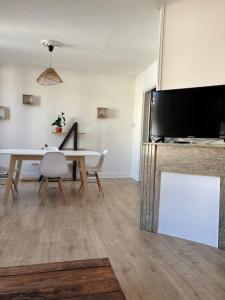 a living room with a dining table and a television at Soleil urbain in Périgueux