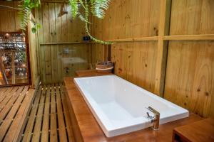 a bath tub in a wooden bathroom with a sink at Seren Glamping in Uvita