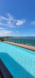 a large swimming pool with a view of the ocean at Flat em frente à Praia in Vitória