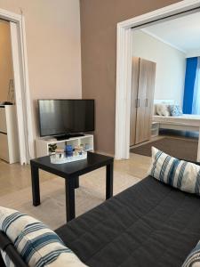 uma sala de estar com um sofá, uma televisão e uma mesa em POSEIDON'S APARTMENT IN PERAIA - SUPERIOR BY THE SEA em Perea