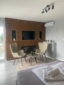 a bedroom with a bed and two chairs and a fireplace at Diamond apartments in Sarajevo
