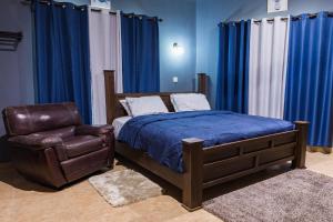 1 dormitorio con 1 cama y silla de cuero en BlueGreen GuestHouse en Accra