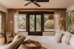 a bedroom with a white bed with a ceiling fan at Aldea Canzul Tulum in Tulum