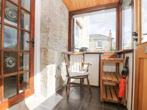 una silla de madera en un porche con ventana en Woodbine Cottage, en Falmouth