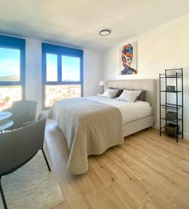Schlafzimmer mit einem Bett, einem Stuhl und Fenstern in der Unterkunft Urban Sky Views over Malaga in Málaga