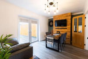 a living room with a dining room table with a couch at Steel Town Lodge - Comfy Home in Port Talbot with Hot Tub, Sky Sports & Dart Board in Port Talbot