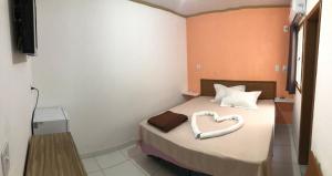 Schlafzimmer mit einem Bett mit einem herzförmigen Kissen in der Unterkunft Pousada 4 estações in Madre de Deus