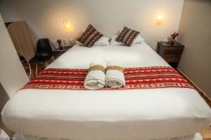 Un dormitorio con una cama blanca con toallas. en RUMIQOLQA Machupicchu Hotel en Machu Picchu