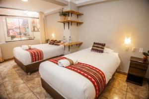 Habitación con 2 camas y mesa. en RUMIQOLQA Machupicchu Hotel, en Machu Picchu