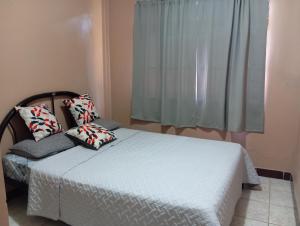 1 dormitorio con cama con almohadas y ventana en Cabinas Miramar, una casa SOLO para ti, en San Isidro