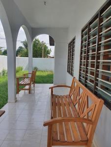 two wooden benches sitting on a porch with windows at Delalie Hotel in Palimé