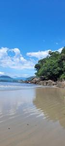 une plage avec des arbres, de l'eau et des nuages dans l'établissement Apto térreo com ar condicionado próximo a praia Maranduba, à Ubatuba