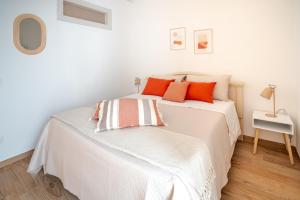 een witte slaapkamer met een bed met oranje kussens bij Dante95 in Polignano a Mare