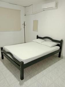 Bett in einem Zimmer mit einer weißen Wand in der Unterkunft Hotel La Nueva Casa del viajero in Aguachica