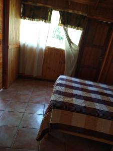um quarto com uma cama com um cobertor xadrez em Raíces del Bolsón em El Bolsón