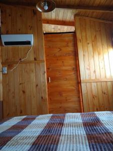 um quarto com uma cama num quarto de madeira em Raíces del Bolsón em El Bolsón