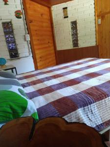 sypialnia z łóżkiem z kocem szachowym w obiekcie Raíces del Bolsón w mieście El Bolsón