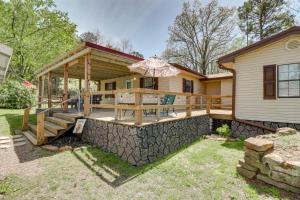 a house with a large deck with an umbrella at Tumbling Shoals Home with Private Yard and Grill! in Heber Springs