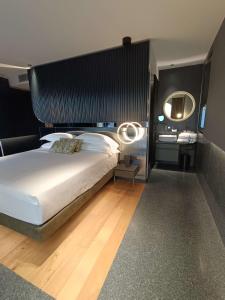 una camera con un grande letto e uno specchio di Hotel Al Caminetto WorldHotels Crafted Adults Only a Torri del Benaco