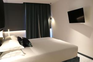 a bedroom with a white bed and a television at Hotel Al Caminetto WorldHotels Crafted Adults Only in Torri del Benaco
