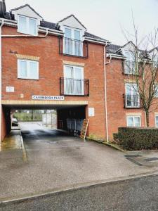 a large red brick building with a garage at Spacious 2 bedroom 2 Bathroom Flat in Hatfield near Hertfordshire University with Private Car Park Sleeps 5-6 in Hatfield