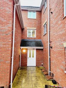 a large brick building with a white door at Spacious 2 bedroom 2 Bathroom Flat in Hatfield near Hertfordshire University with Private Car Park Sleeps 5-6 in Hatfield