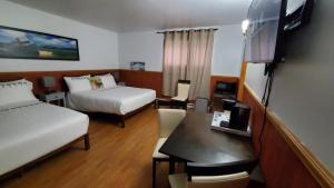Cette chambre comprend deux lits et un bureau. dans l'établissement hôtel Fleurs Karaïbes, à Saint-Alexandre-de-Kamouraska