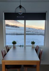 uma mesa de jantar com cadeiras e uma grande janela em Tungukot sumarhús em Akureyri