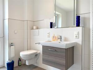 une salle de bains blanche avec toilettes et lavabo dans l'établissement Haus "Friesland 10", Am Alten Deich 15c, à Dangast 21 autres photos