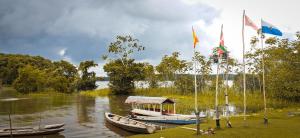 twee boten zijn aangemeerd op een rivier met vlaggen bij Campamento Txoko de Shapshico in Puerto Franco