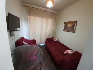 Porto Matroh Tours في مرسى مطروح: غرفة معيشة مع أريكة حمراء وطاولة زجاجية