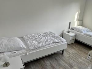 a white bedroom with a bed and a night stand at Nordsee Park Haus Friesland 6 P112 in Dangast