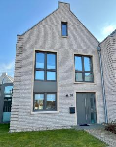 a white brick house with windows and a door at Nordsee Park Haus Friesland 6 P112 in Dangast