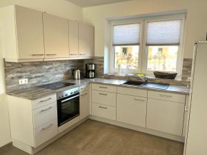 une cuisine avec des armoires blanches et un évier dans l'établissement Nordsee Park Haus Friesland 7 P113, à Dangast