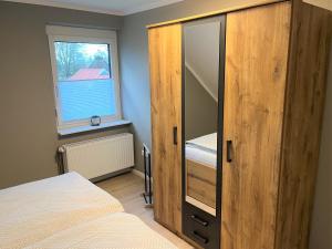 1 dormitorio con armario de madera, cama y ventana en Apartment FriesenLück, en Bockhorn