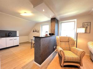 ein Wohnzimmer mit einem Stuhl und eine Küche in der Unterkunft Apartment FriesenLück in Bockhorn