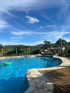 une piscine d'eau bleue et une terrasse en bois dans l'établissement Pousada Serra Morena, à La Serra do Cipo