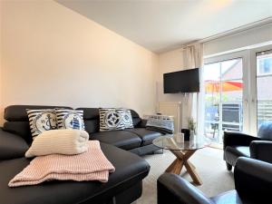 a living room with a black couch and a glass table at Haus Auszeit, Bordumer Str 16A, 70qm in Dangast